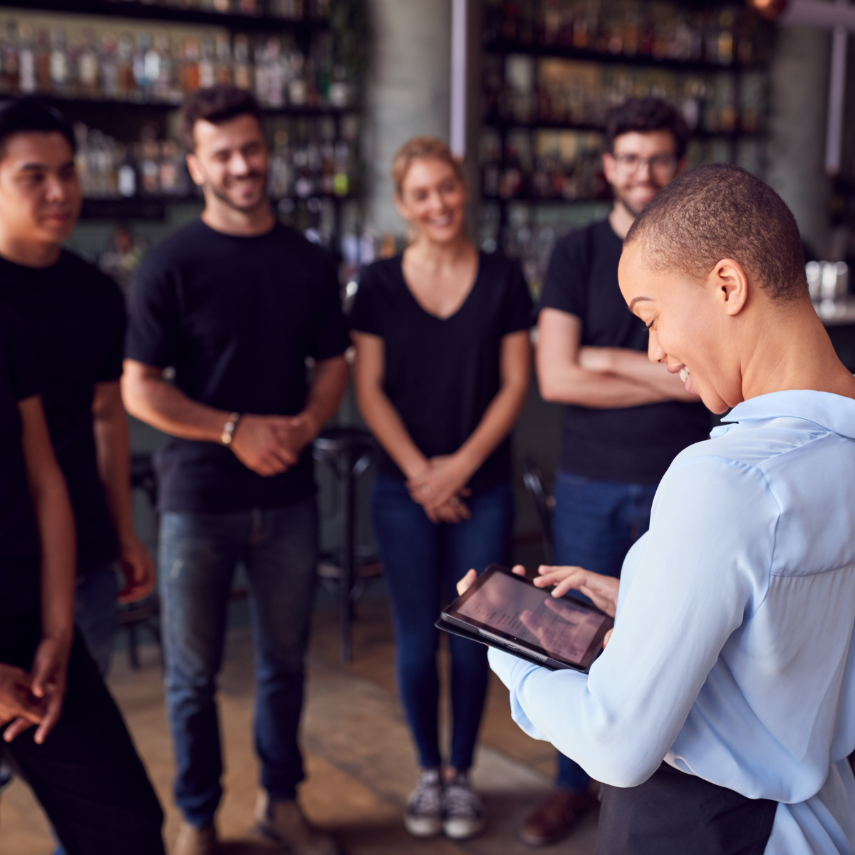 Manager restauracji rozmawiający z zespołem pracowników przy barze